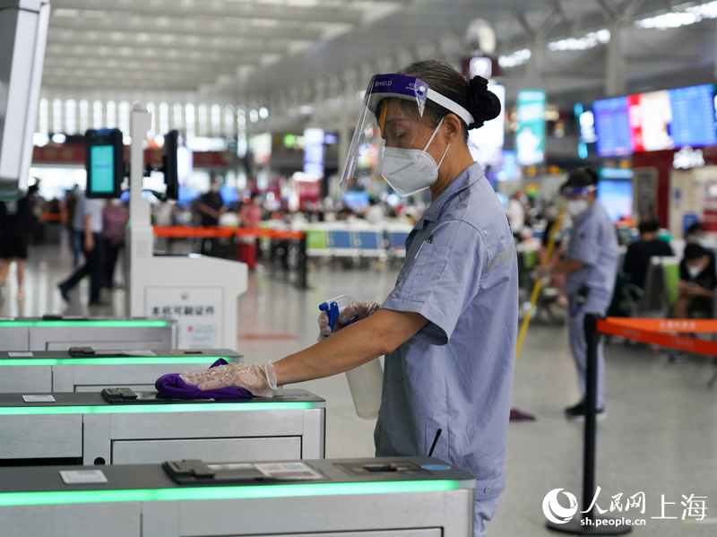 保潔員在上海虹橋火車站對進站閘機進行擦抹消毒作業(yè)。