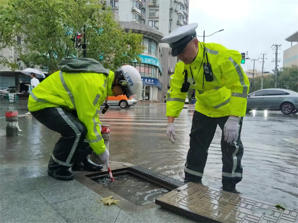 四大隊民警蘇張靈、輔警王志斌在牡丹江路寶林路積水點對下水道進行清理。